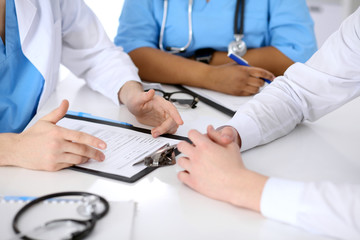 Two doctors and male patient discussing medical history at the table, close up