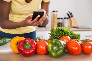 Close-up Of A Woman Using Mobile Phone In Kitchen