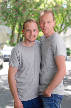 Two gays standing on a street at at sunny day, happy smiling and