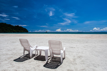 Double white chairs on the beach with blue sky  background