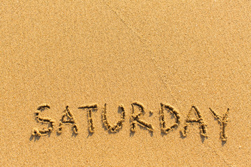 Saturday - inscription by hand on a light-golden beach sand.