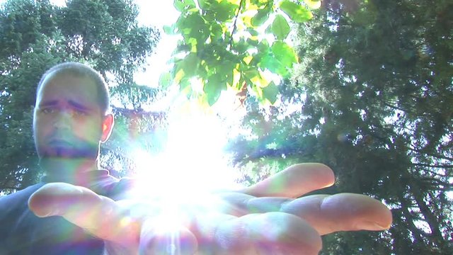 Man opening his hand to show sun in it
