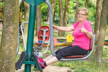 Fototapeta na wymiar Senior woman exercising lower body on outdoor gym, healthy lifestyle
