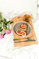 Obraz na płótnie Canvas Breakfast in bed, Oatmeal pancakes with grapefruit, tea and Peon