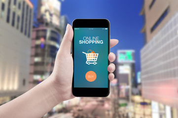 Hand holding mobile smart phone with online payment screen on city background