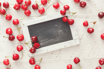 Naklejka na ściany i meble Fresh cherries around empty chalkboard. 