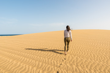 Fototapeta na wymiar Girl walking on sand dunes in Gran Canaria, Spain
