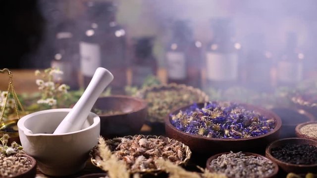 Herbs, berries and flowers with mortar, on wooden table background