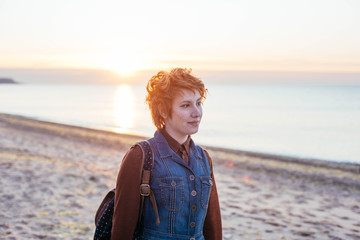 young caucasian redhead woman having fun on beach at sunset