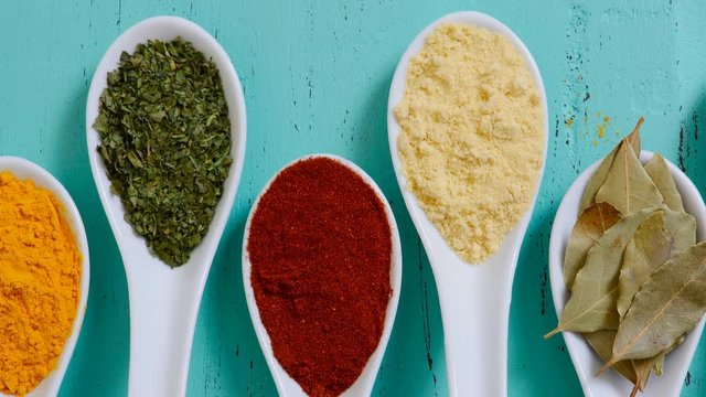 Colorful Cooking Spices And Herbs In White Spoons On Vintage Aqua Blue Table Overhead, Panning Across And Zoom Out.