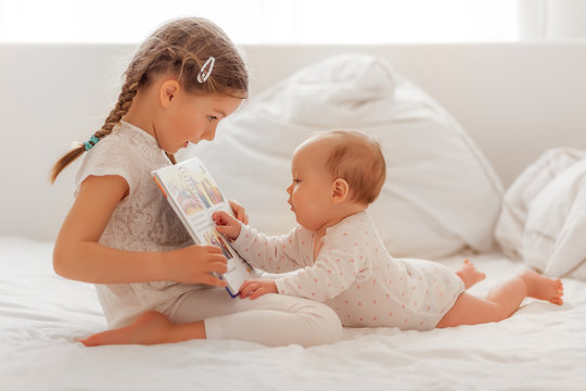 Mädchen liest ihrer kleinen Schwester etwas vor