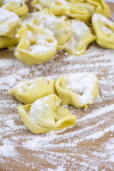 Fototapeta na wymiar Several yellow ravioli on the wooden table with flour