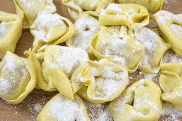 Pile of yellow ravioli with flour