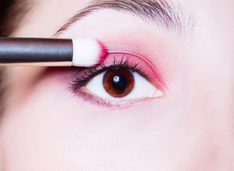 Eye makeup. Woman applying pink eyeshadow powder