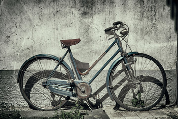 Fototapeta na wymiar Antica bici appoggiata in una parete - Vintage