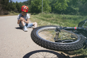 Boy is lying hurt after a bicycle accident. Kids safety concept