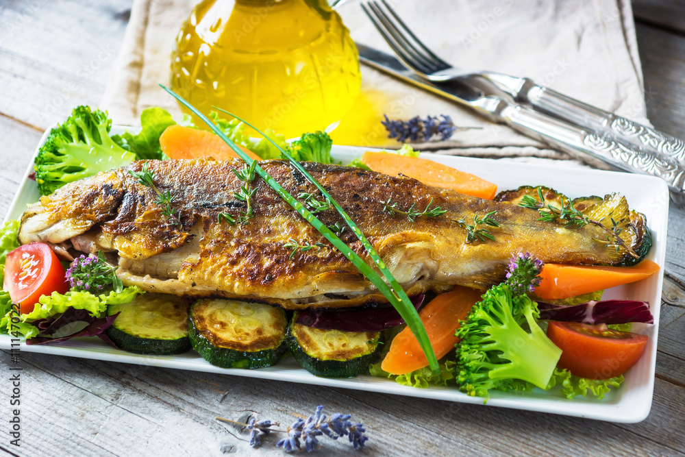 Poster grilled trout with vegetables on wooden background