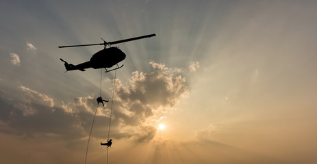 Silhouette of helicopter, soldiers rescue helicopter operations on sunset sky background. © yotrakbutda