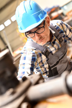 Metalworker with hardhat working on machine