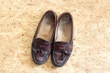 old brown leather shoes on chipboard background