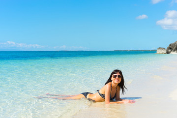 Fototapeta premium Young happy woman in black bikini enjoys sunny day on beach. Tropical vacation