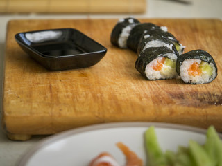 Sushi on a cutting board with soy sauce and ingredients.