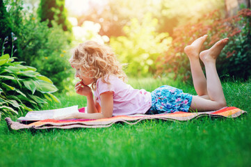 Fototapeta na wymiar cute child girl reading book in summer garden outdoor. Kids learning on summer vacations.