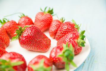 Ripe strawberry fruits on a white plate
