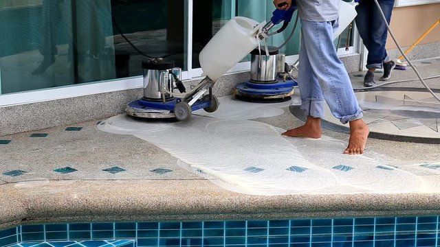 Worker cleaning stone floor with machine and chemical