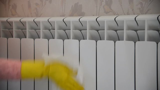 Female hand in  rubber glove cleans heating radiator