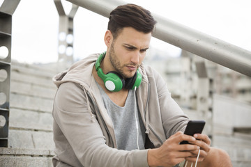 Young man outdoors texting and looking worried