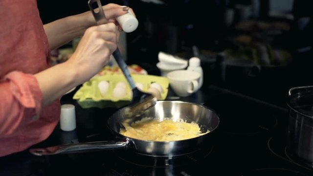 Woman hands mixing scrambled eggs on frying pan 