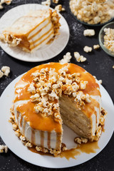 Vanilla biscuit with white cheesse cream decorated caramel topping and popcorn, black background, top view