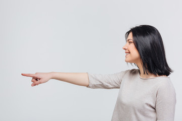 Casual young woman pointing finger aside