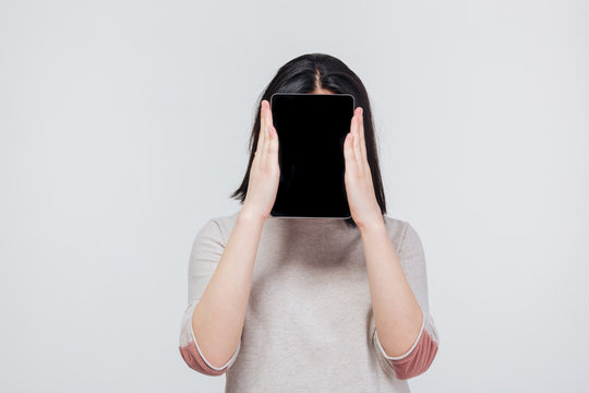 Pretty brunette girl cover her face with tablet computer