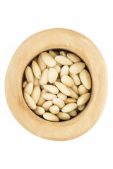 Blanched almonds  in wooden bowl, top view, on white background