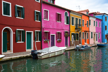 Fototapeta na wymiar Multicolored walls of houses and motor boats on Burano island, Venice