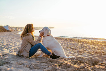 young beautiful woman playing with labrador dog on the beach - Powered by Adobe