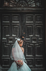 Fototapeta na wymiar Beautiful blond bride in white dress posing near old wooden door