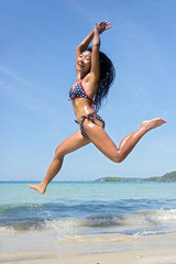 Attractive woman in bikini jumping on the sea beach