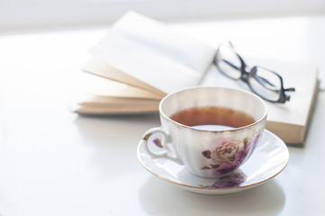Cup of tea, old book and glasses