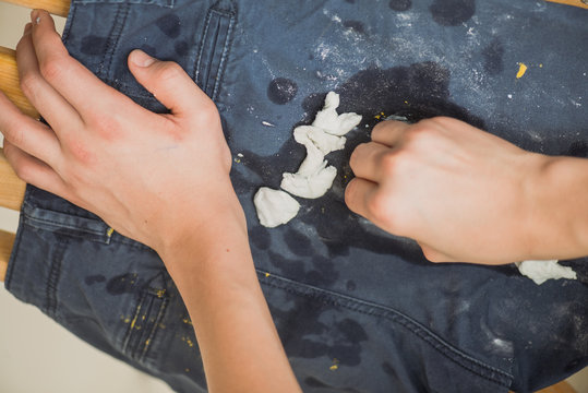 Boy Wipes The Paint On His Pants. Blue Jeans And Sneakers Stained With Yellow Paint. Top View.