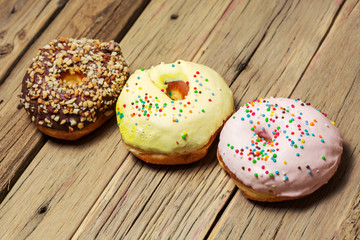Three donut with colorful decor. Isolated on wooden background