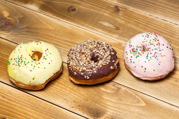 Three donut with colorful decor. Isolated on wooden background