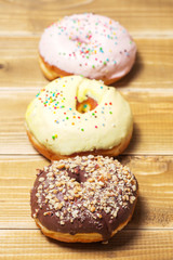 Three donut with colorful decor. Isolated on wooden background