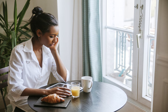 Young woman using digital tablet at breakfast table
