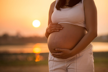 Pregnant woman relaxing lakeside sunset background