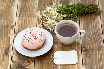 Cup of black coffee with pink donut on a plate 