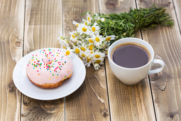 Cup of black coffee with pink donut on a plate 