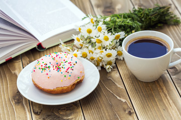 Cup of black coffee with pink donut on a plate 